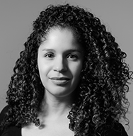 Black and white portrait of Christina L. De León who has curly hair and is wearing a black shirt.