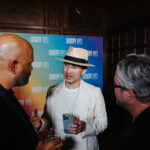 3 men converse in front of a brightly colored Cooper Hewitt National Design Award backdrop.