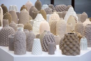 Multiple clay pots with varying textures and shapes displayed on a white table.