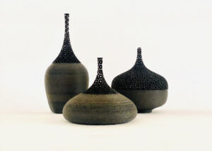 Three pots of different shapes and sizes made of clay and lace-like metal work.