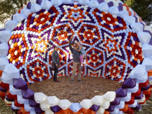 A group of people stand marveling in the center of a kaleidoscopic structure.