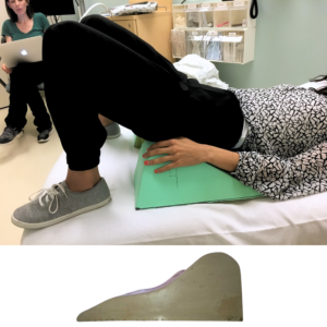 Patient in doctor's office resting their pelvis on an elevated green foam cushion.