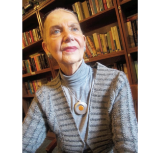 An elderly woman wearing a silver necklace with a medical alert button.