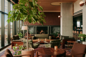 A modern living room with a fireplace decorated in sleek furniture and rich green and brown earth tones.