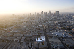 A birds eye view of Los Angeles depicting a small complex of modern white buildings amongst a sea of dark grey buildings.