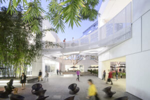 The courtyard of a modern white two-story building with a pedestrian bridge.