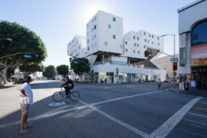 Facade of a modern white boxy building decorated with windows on a city street corner.