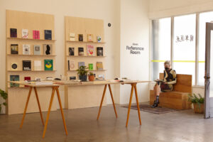 A modern style reading room displaying books on a large table and shelves.