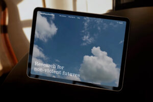 A touchscreen tablet showing the homepage of World Peace Foundation's website which displays in a large font the words [Research for Non-Violent Futures].